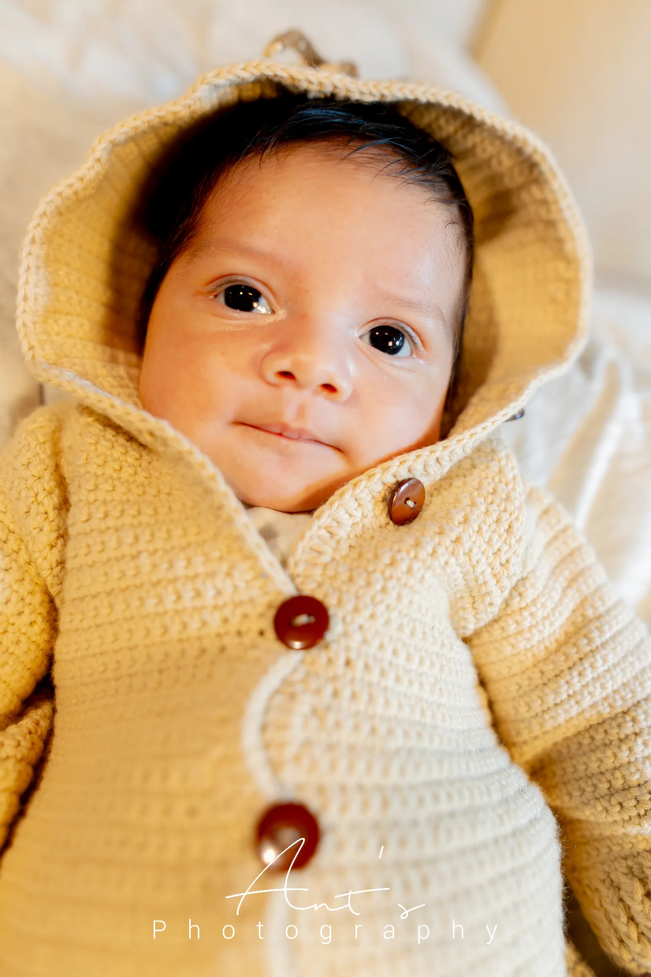 Cairo looking toward the camera in a cream knitted hooded outfit