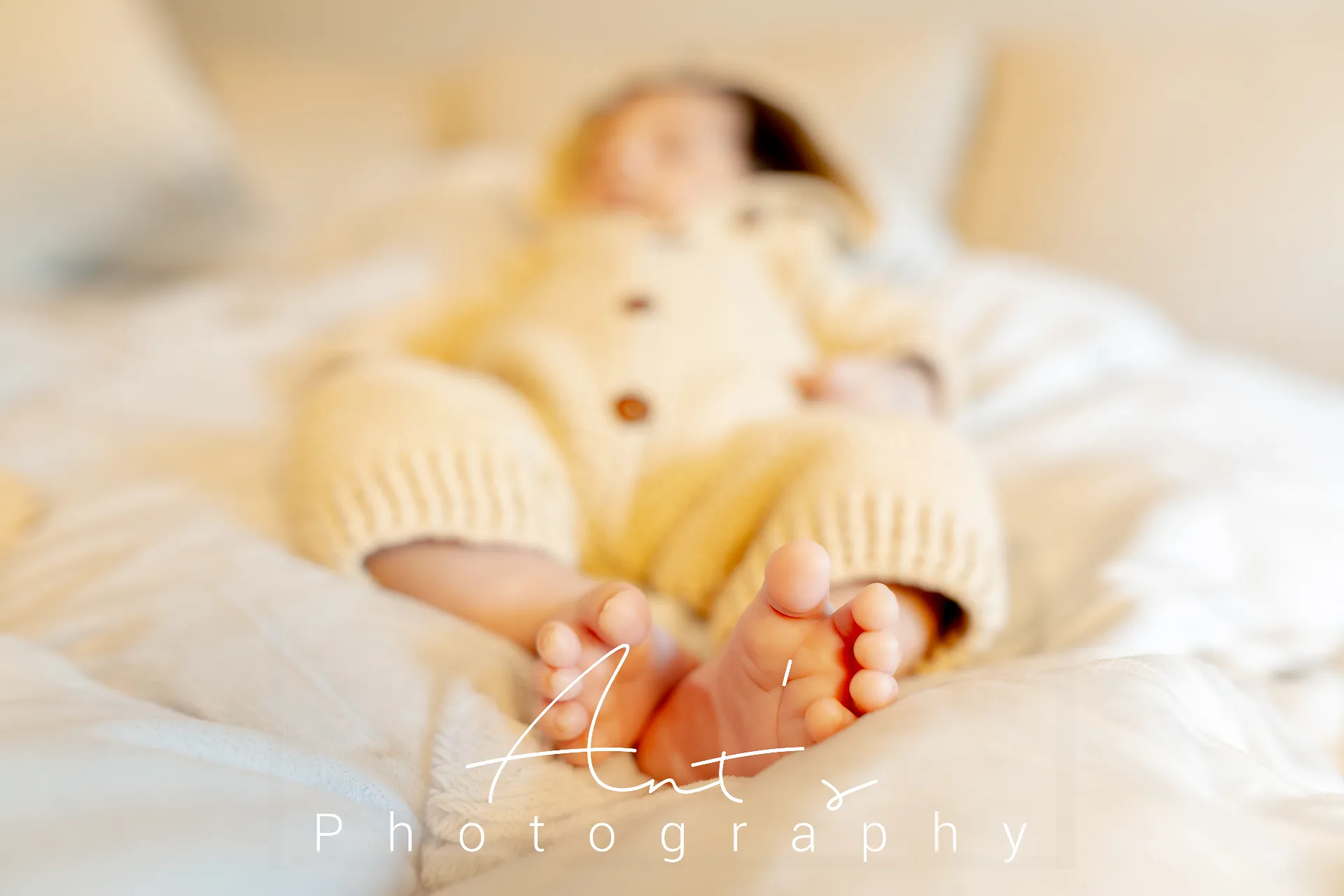 Close-up of Cairo’s tiny bare feet with a cream knitted outfit in the background